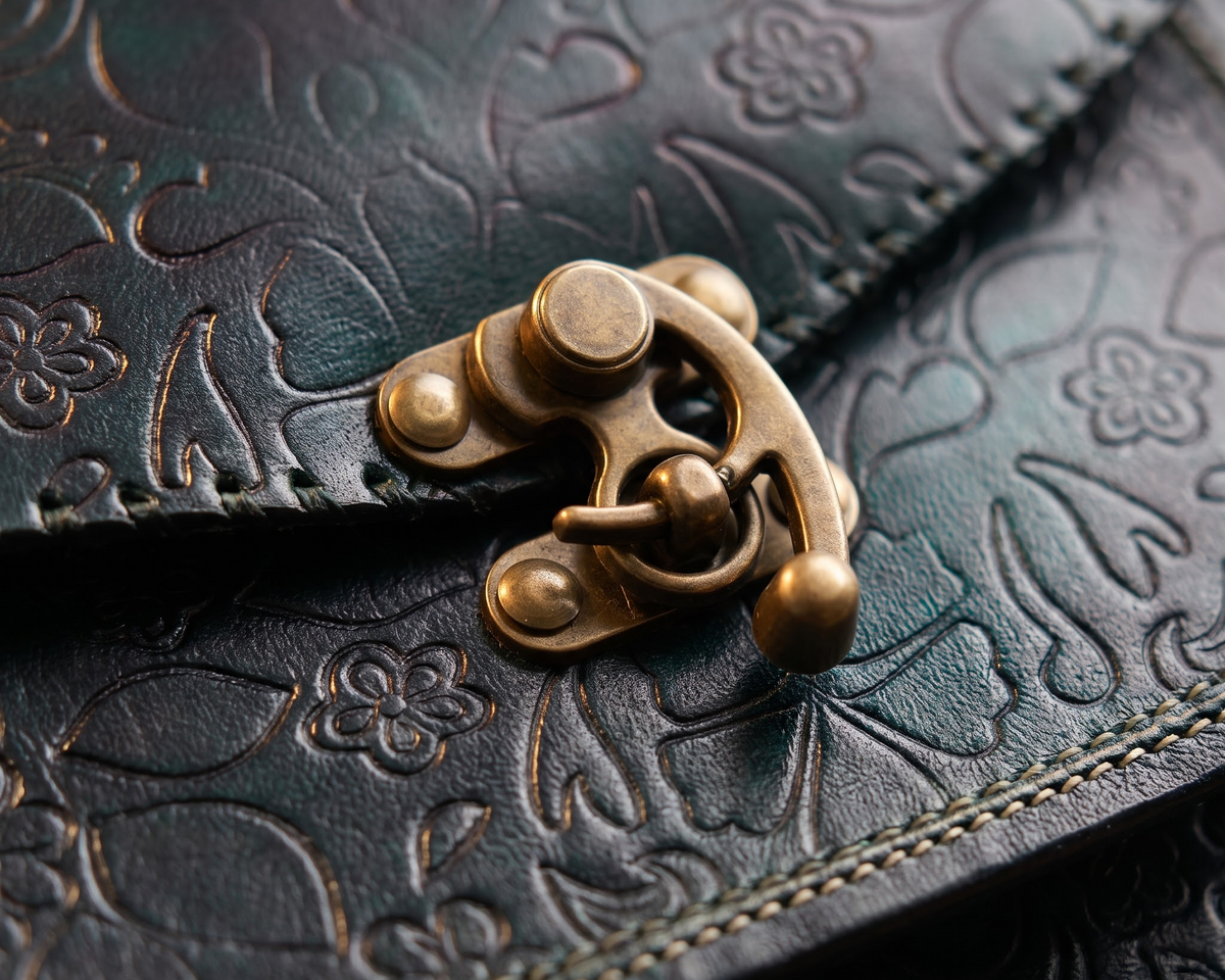 Close-up of a dark embossed leather item with an antique brass clasp and the text 'ANTIQUE BRASS HARDWARE' in the lower right corner.